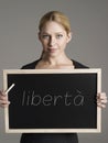 Portrait of young businesswoman holding blackboard with Italian text libertÃÂ  (Freedom)
